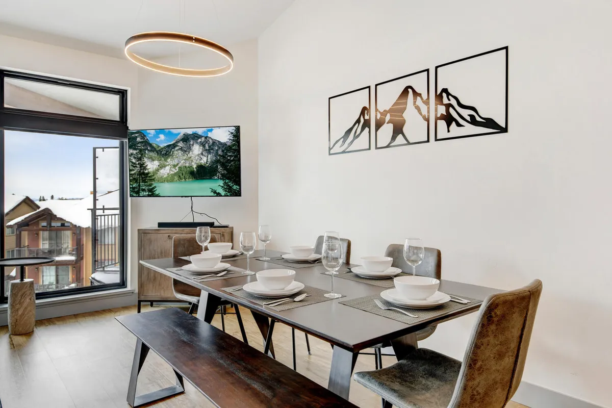 This welcoming dining area features a dining table set for a meal, mountain-inspired artwork, and a large window that brings in ample natural light and views. The setting is ideal for family dinners, social gatherings, or casual brunches, capturing the lively yet relaxing spirit of downtown living.