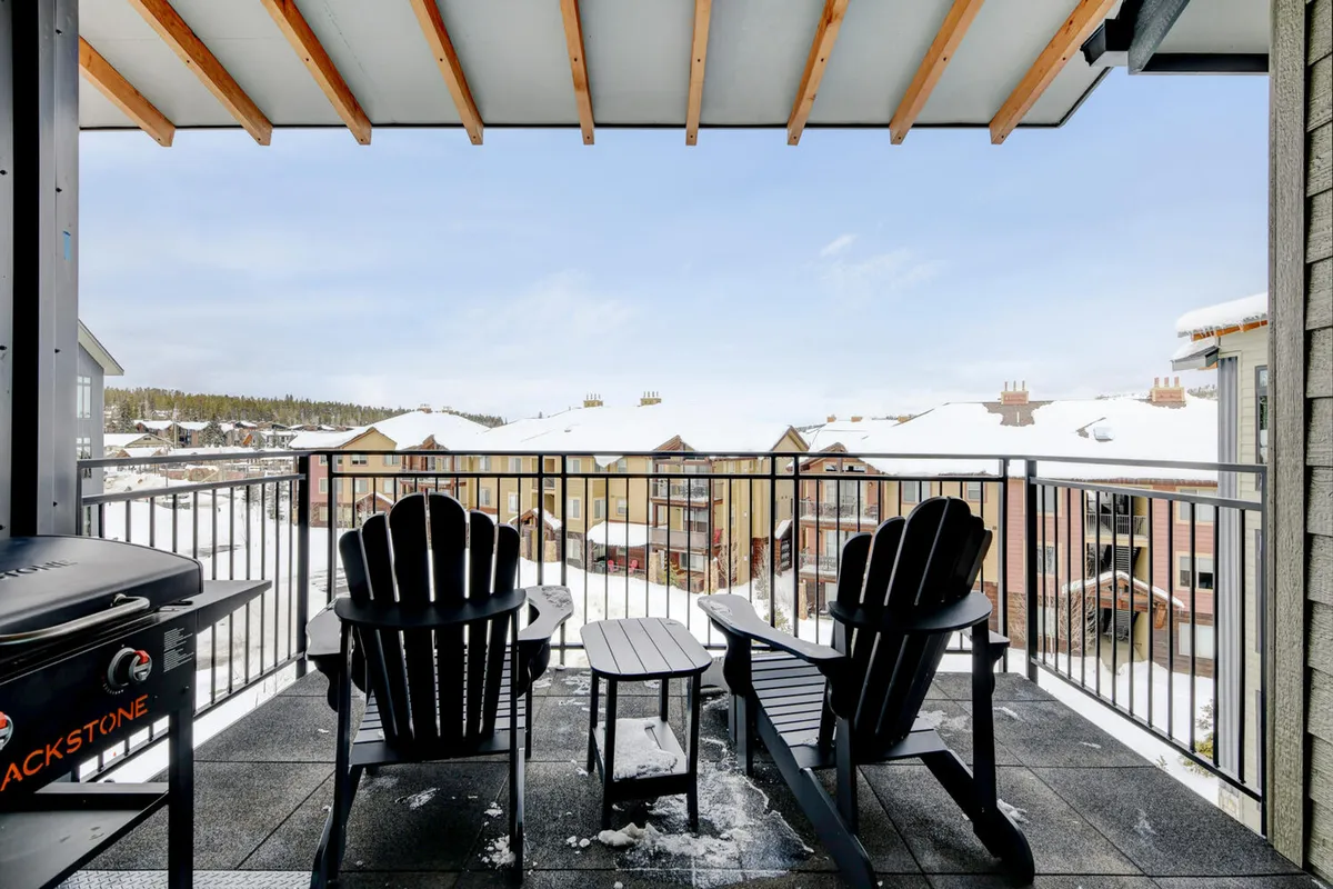 A cozy exterior patio scene with Adirondack chairs and a small table, overlooking snow-covered rooftops. The setting suggests a comfortable place to gather outdoors, socialize, and enjoy mountain views. The snow and the relaxed seating arrangement evoke the après-adventure atmosphere described in the section.