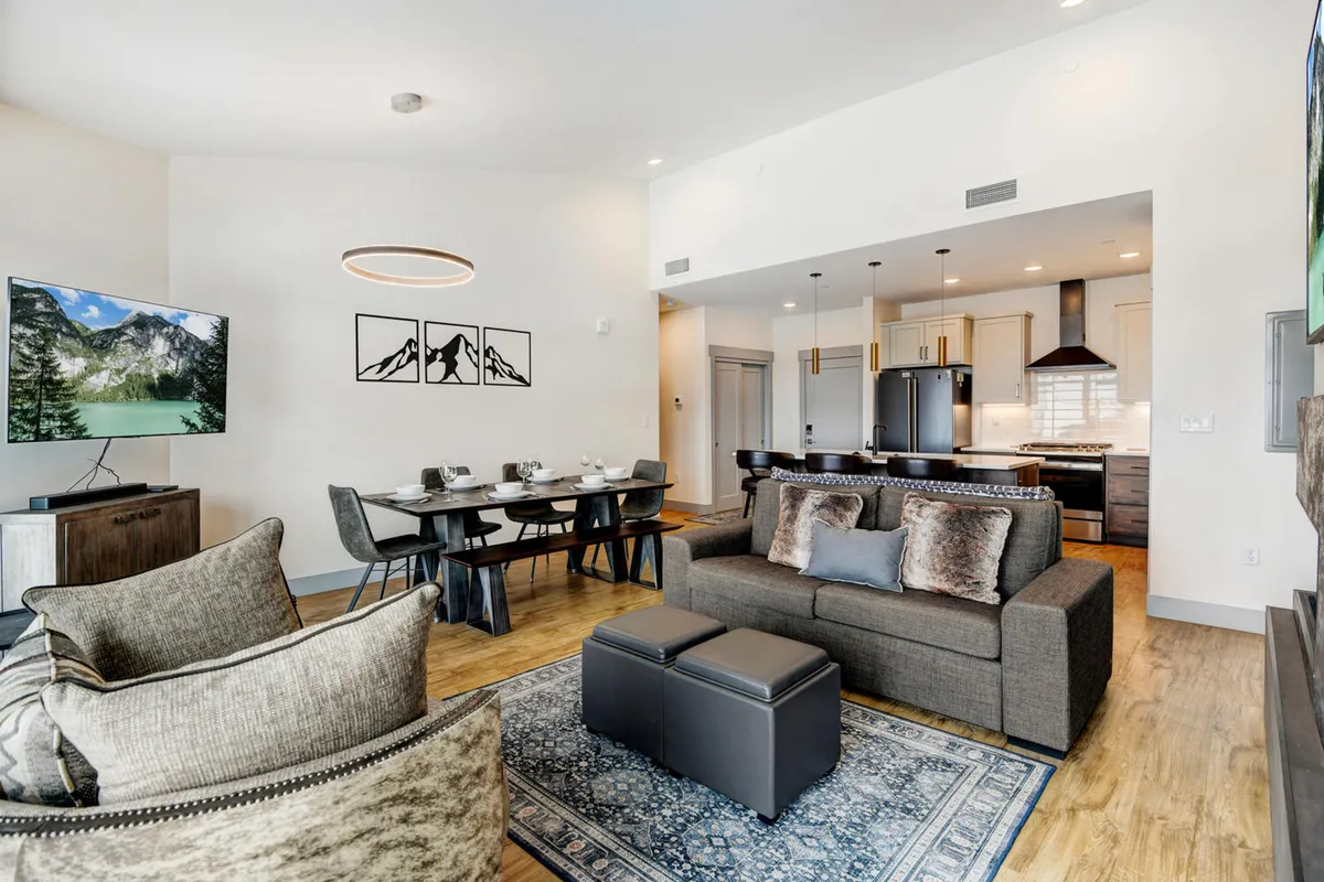 This image features a comfortable and inviting living room and dining area. The scene highlights a sofa for lounging, a dining table for meals or gatherings, a television ideal for movie nights, and artwork that adds a touch of personality. The layout embodies an open-plan concept, perfect for both relaxation and socialization, and matches the 'heart of Winter Park' vibe described in the section.